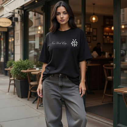 Woman wearing a black t-shirt with a logo and text, standing on a city street.