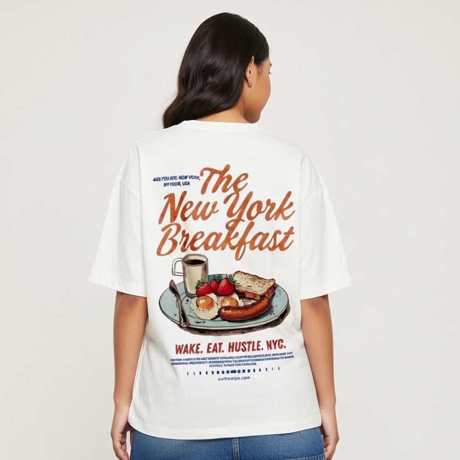 Person wearing a white t-shirt with 'The New York Breakfast' design on a plain background