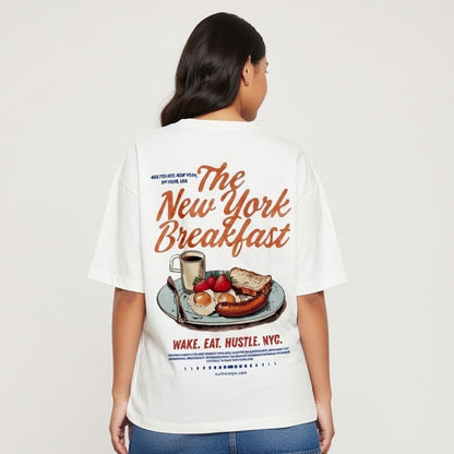 Person wearing a white t-shirt with 'The New York Breakfast' design on a plain background