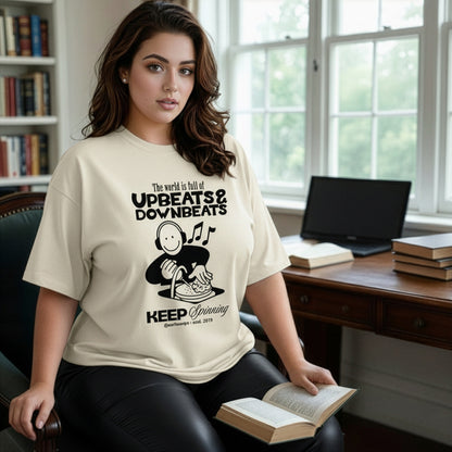 Woman wearing a t-shirt with a graphic design, sitting in a room with books and a laptop.