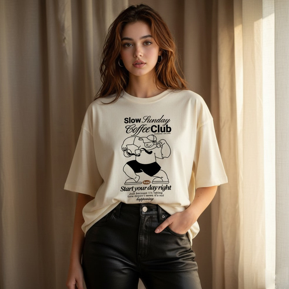 Woman wearing a t-shirt with 'Slow Sunday Coffee Club' design against a neutral background