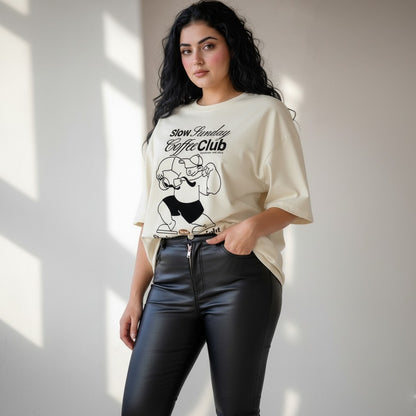 Woman wearing a white t-shirt with a graphic design and text, standing against a neutral background.