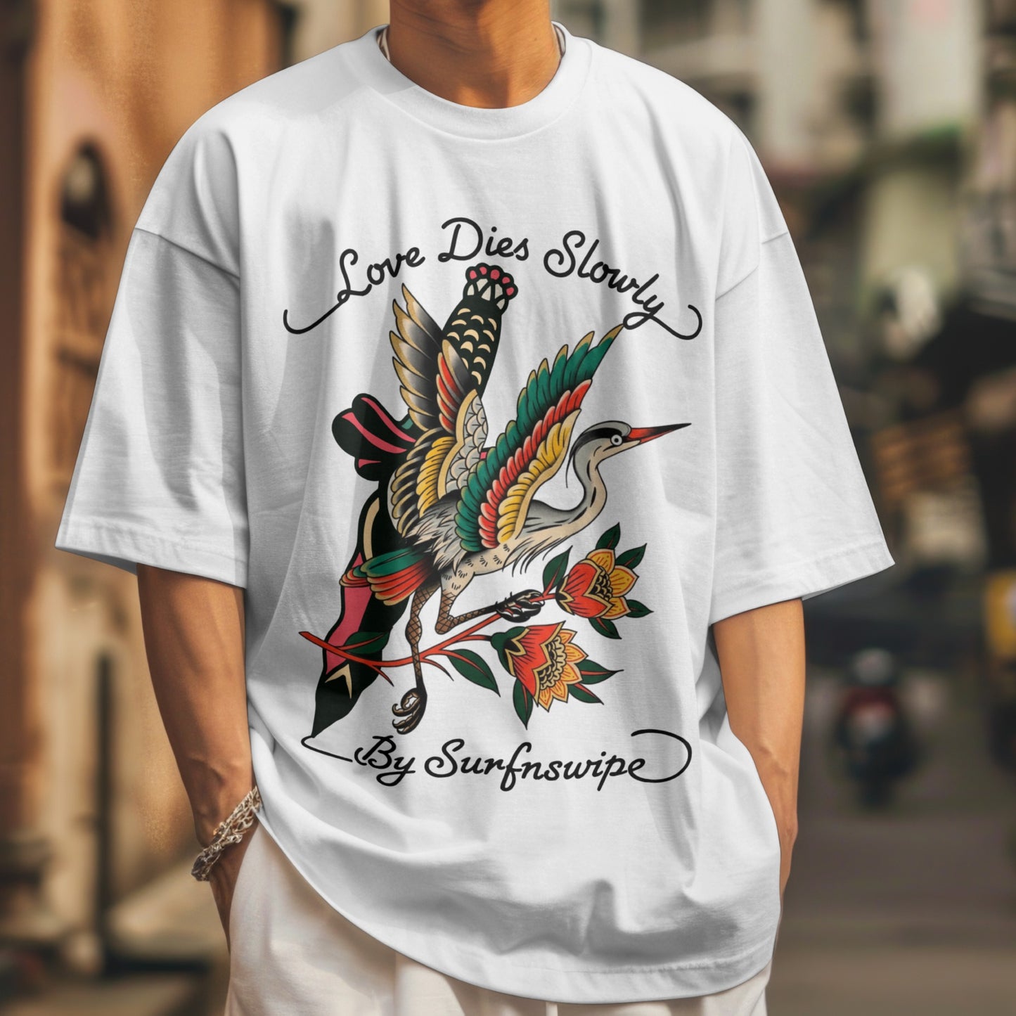 Person wearing a white t-shirt with a colorful bird design and text.