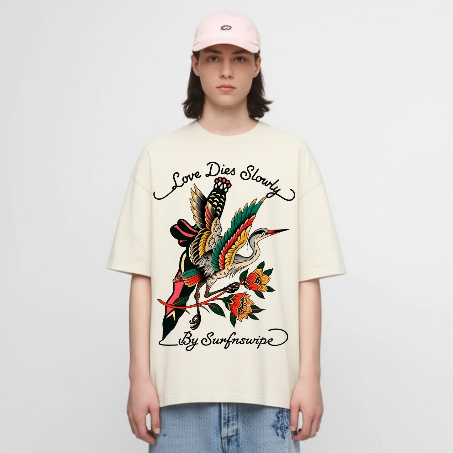 Person wearing a cream t-shirt with a colorful graphic design and text on a white background