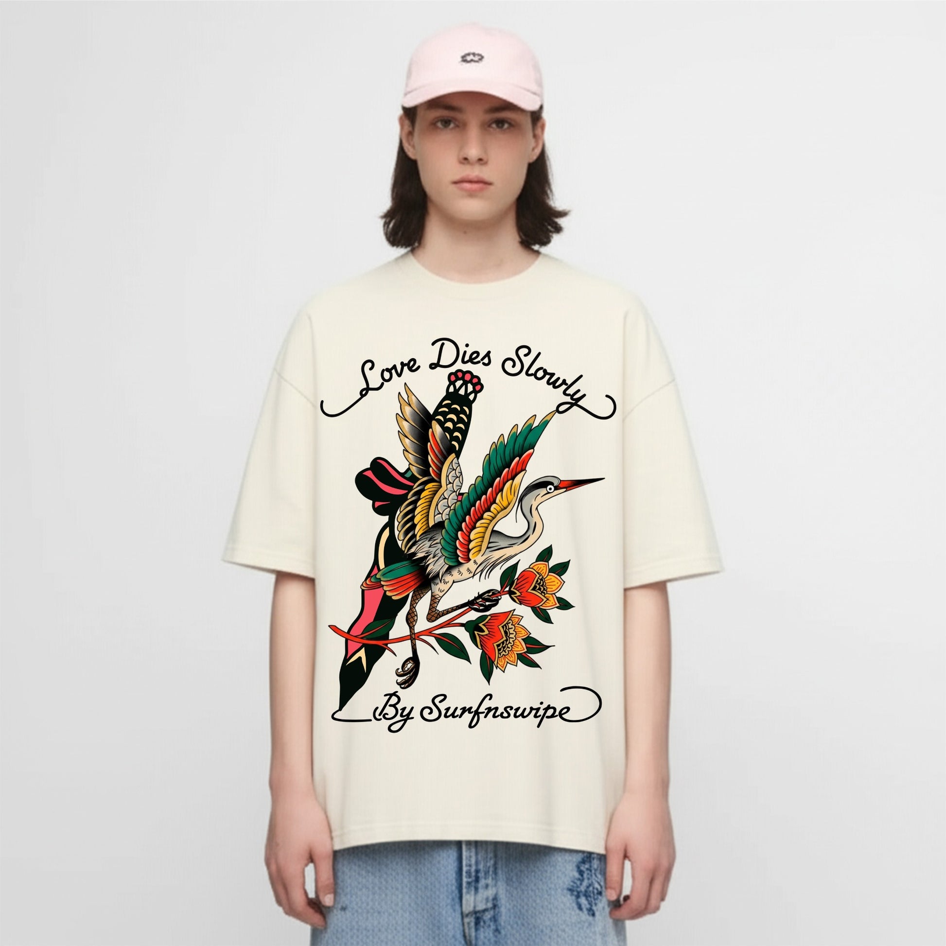 Person wearing a cream t-shirt with a colorful graphic design and text on a white background