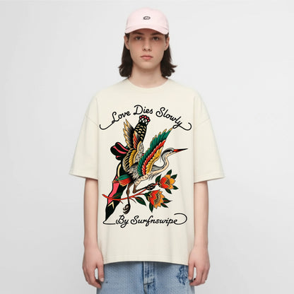 Person wearing a cream t-shirt with a colorful graphic design and text on a white background