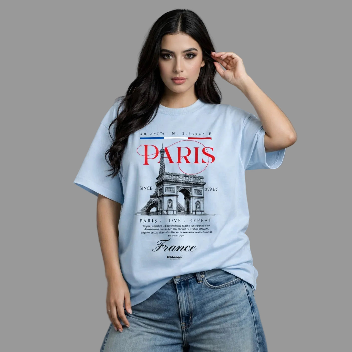 Woman wearing a light blue t-shirt with Paris-themed design on a gray background