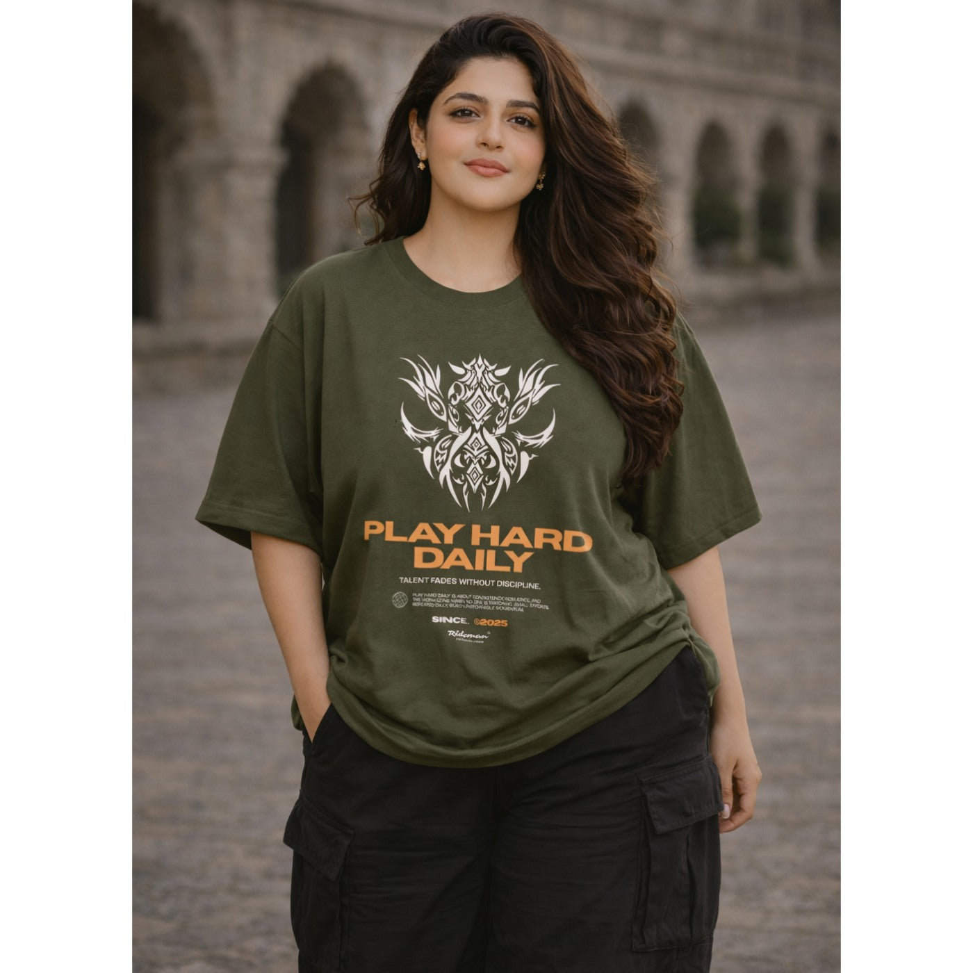 Woman wearing a green t-shirt with 'Play Hard Daily' text and design.