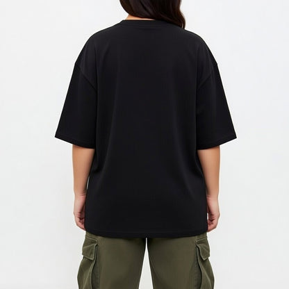 Person wearing a black oversized t-shirt and green cargo pants on a white background