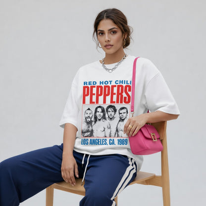 Woman wearing a 'Red Hot Chili Peppers' t-shirt and sitting on a chair with a pink bag.