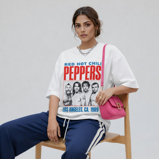 Woman wearing a 'Red Hot Chili Peppers' t-shirt and sitting on a chair with a pink bag.