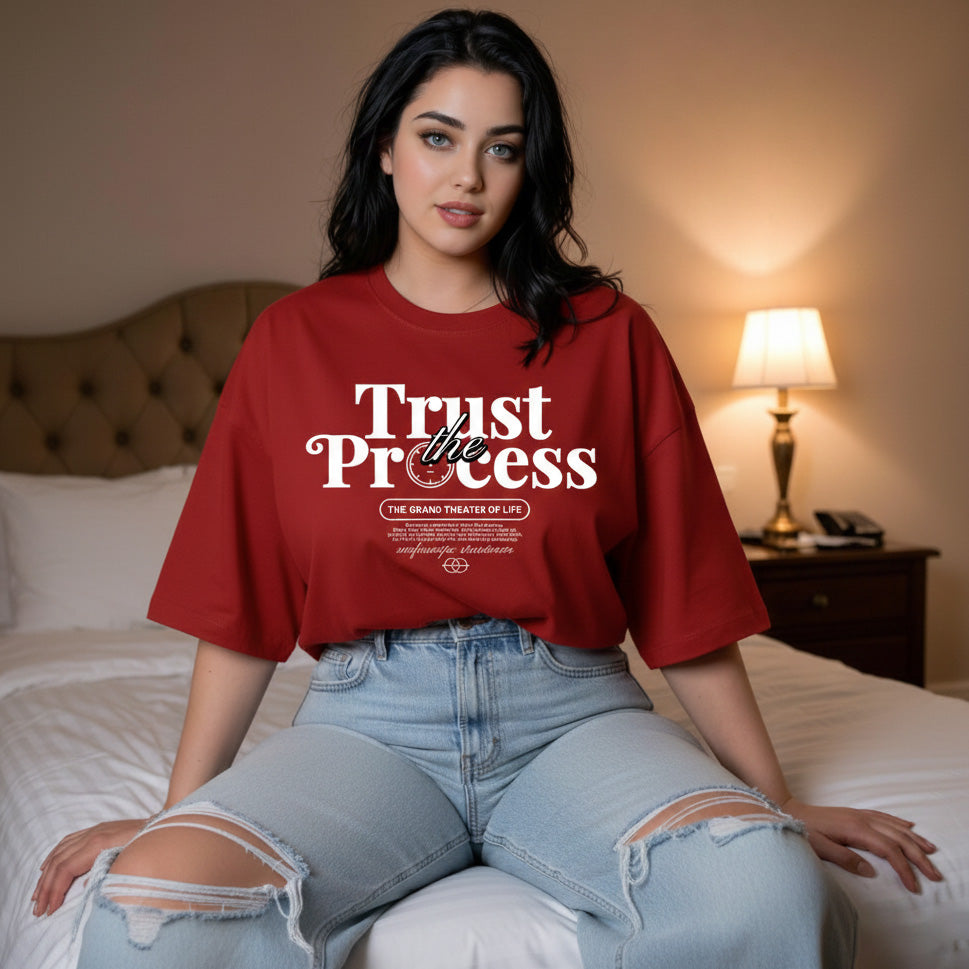 Woman wearing a red 'Trust the Process' t-shirt in a bedroom setting