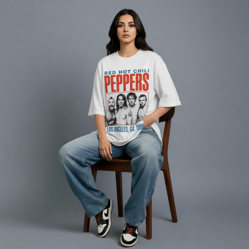 Person wearing a 'Red Hot Chili Peppers' t-shirt sitting on a chair against a gray background