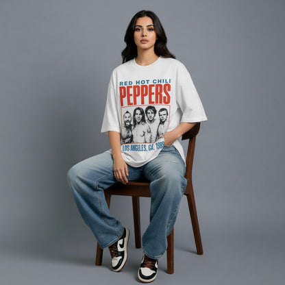 Person wearing a 'Red Hot Chili Peppers' t-shirt sitting on a chair against a gray background