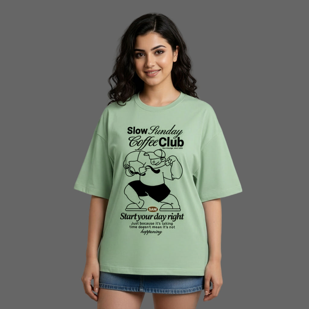 Woman wearing a green t-shirt with 'Slow Sunday Coffee Club' design on a gray background