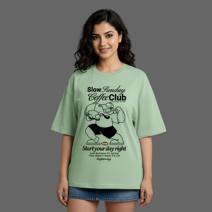 Woman wearing a green t-shirt with 'Slow Sunday Coffee Club' design on a gray background