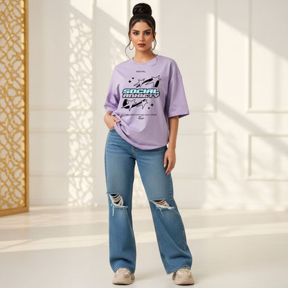 Woman wearing a purple oversized t-shirt and blue jeans in a bright room.