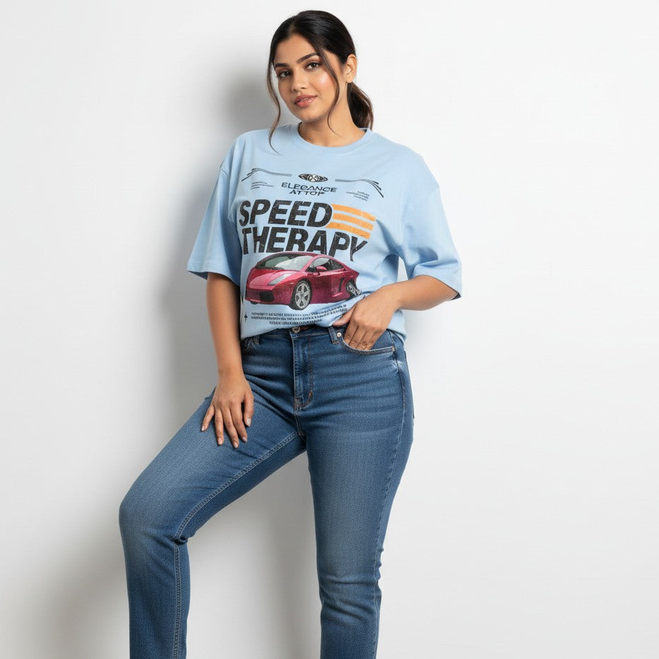 Woman wearing a light blue t-shirt with a graphic design and text, standing against a plain background.