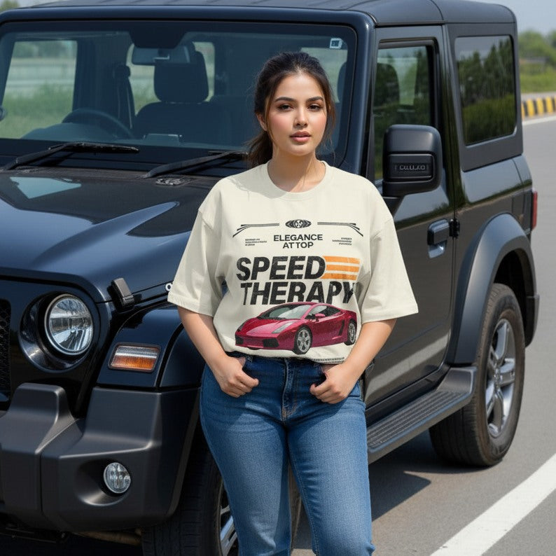 Woman wearing a t-shirt with a car graphic and text, standing next to a black SUV on a road.