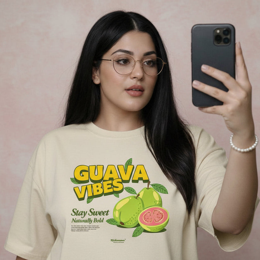 Woman wearing a 'Guava Vibes' t-shirt taking a selfie against a floral wall.