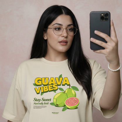 Woman wearing a 'Guava Vibes' t-shirt taking a selfie against a floral wall.