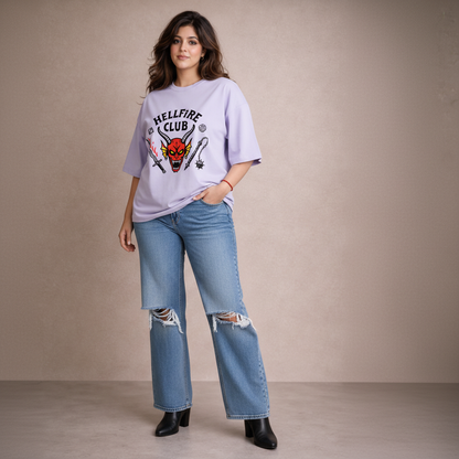 Woman wearing a 'Hellfire Club' t-shirt and ripped jeans against a plain background