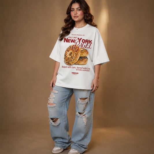 Person wearing a 'New York Bagel' t-shirt and ripped jeans on a brown background