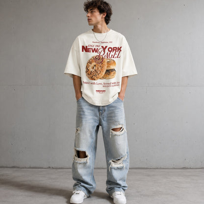 Person wearing a graphic t-shirt and ripped jeans against a plain background