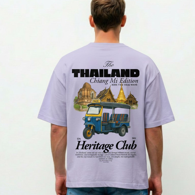 Person wearing a light purple t-shirt with a graphic design on the back, featuring text and an illustration of a tuk-tuk and traditional buildings.