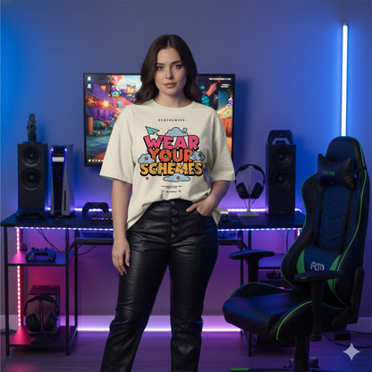 Model wearing cream oversized unisex t-shirt with colorful cloud graphic, standing beside gaming chair