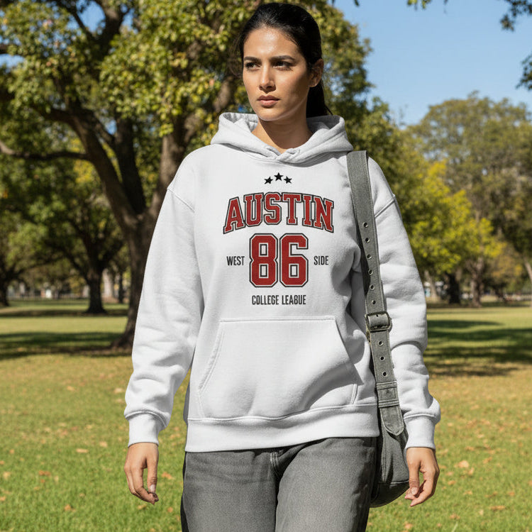 Woman wearing a white hoodie with 'Austin 86' text, walking outdoors.