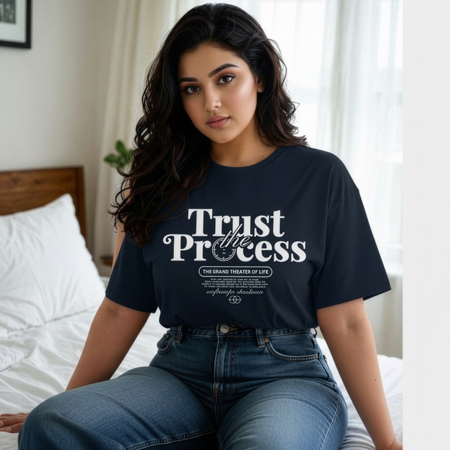 Woman wearing a black t-shirt with 'Trust the Process' text, sitting on a bed.