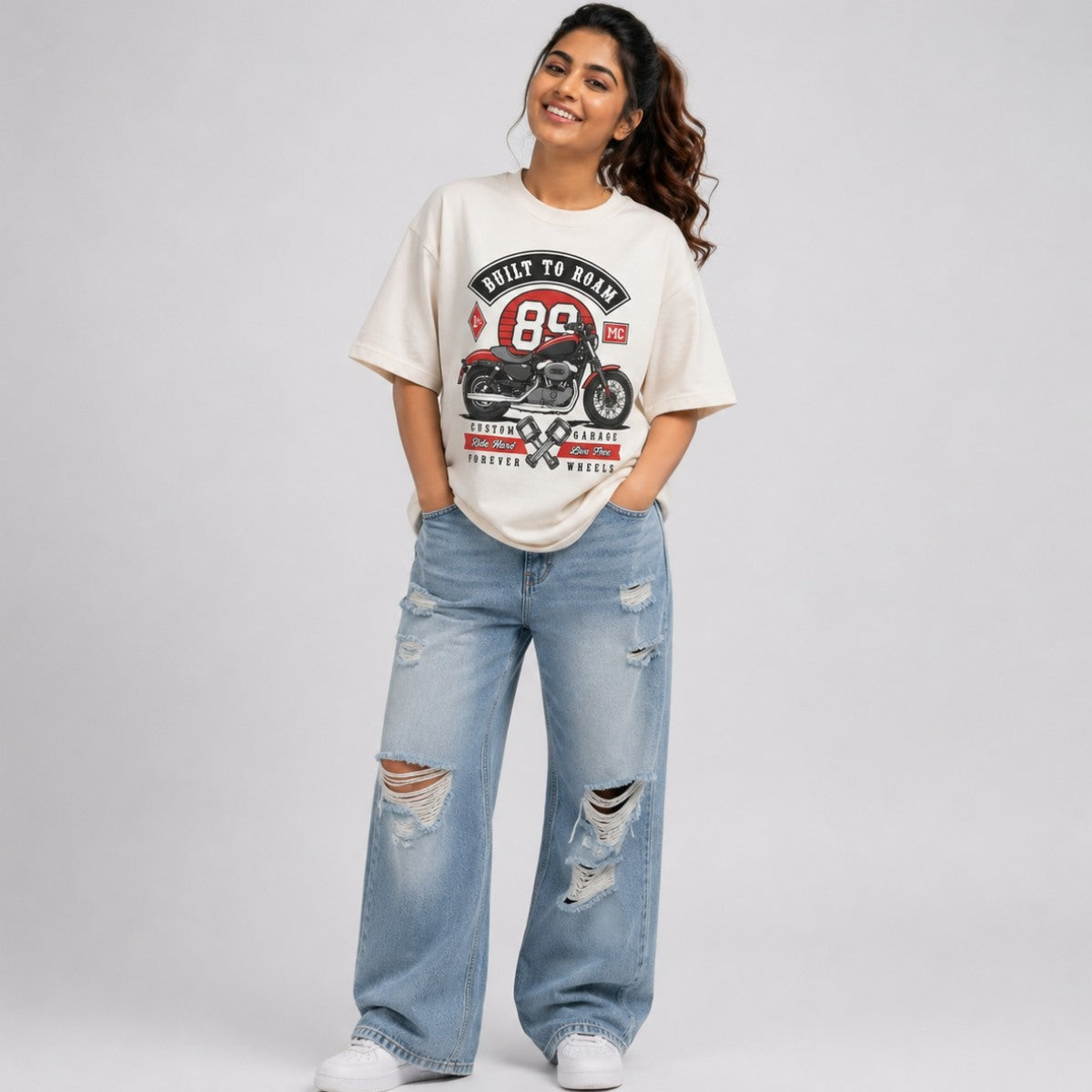 Woman styling a off-white oversized vintage biker graphic tee with ripped jeans streetwear style