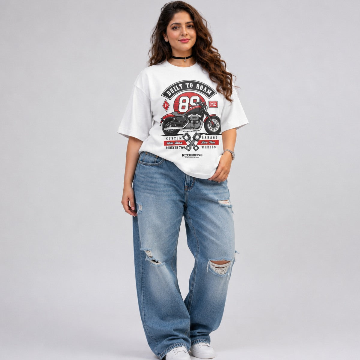 Woman styling a light blue oversized vintage biker graphic tee with ripped jeans streetwear style