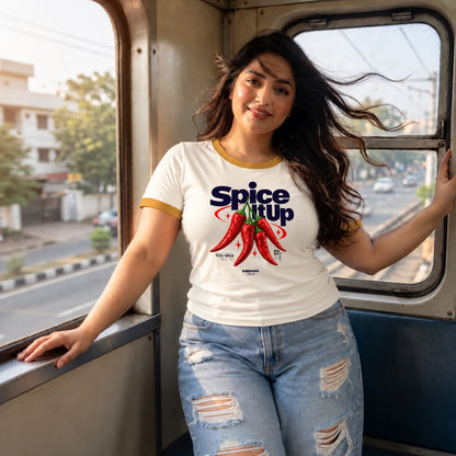 Woman wearing ecru ringer T-shirt with mustard trim and "Spice It Up" red chili print, styled with denim mini skirt and white sneakers