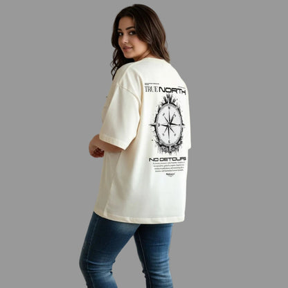 Woman wearing a cream t-shirt with 'True North' graphic design indoors.