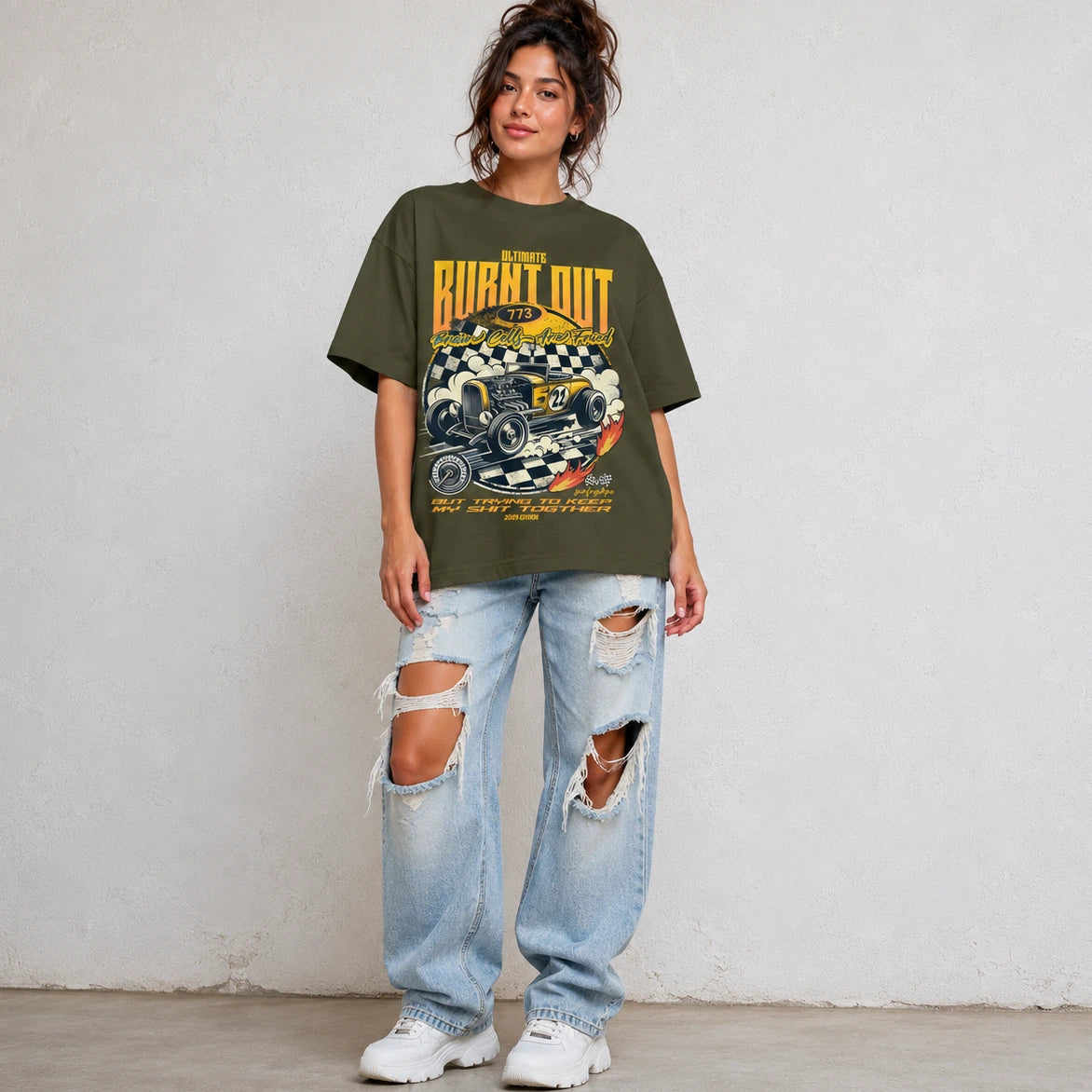 Woman wearing SURFNSWIPE Burnt Out Hot Rod oversized T-shirt in olive styled with ripped wide-leg jeans