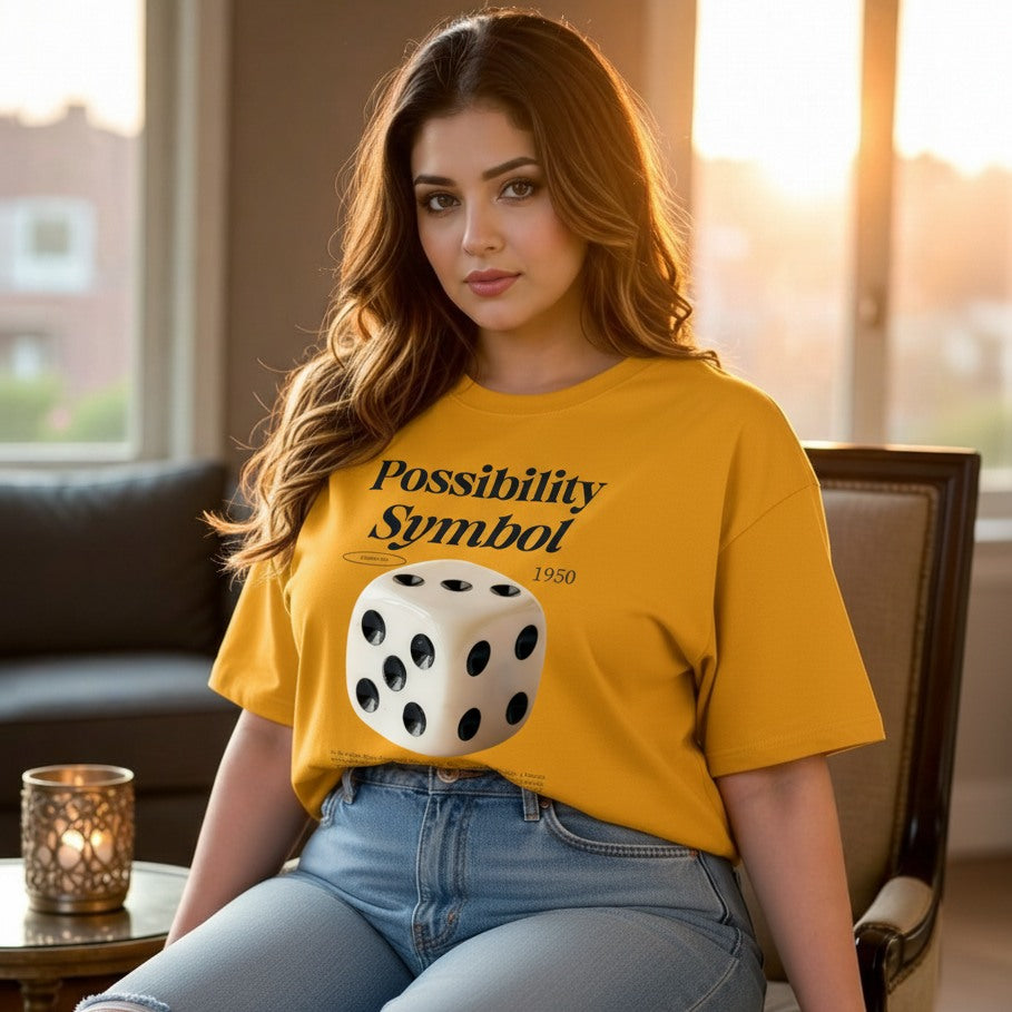 Woman wearing a yellow t-shirt with a dice graphic and text, sitting indoors.